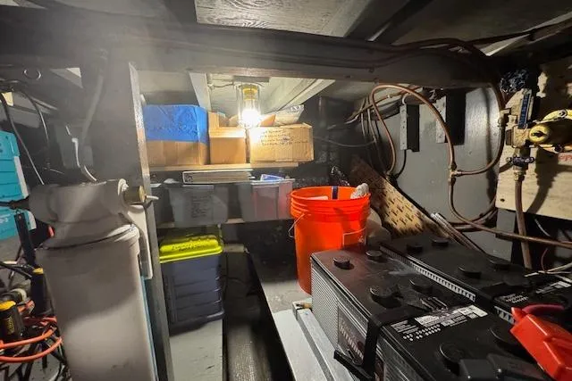 Slide: The Image of 1974 Chris-Craft 47 Commander engine room with storage boxes, battery, and wiring. - 56