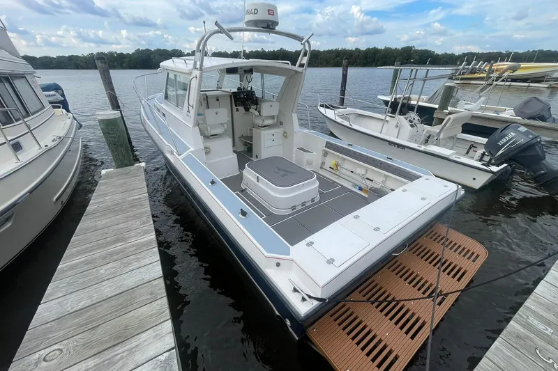 Slide: The Image of 1995 Albin 28 boat docked, featuring spacious deck and seating, surrounded by watercraft. - 2