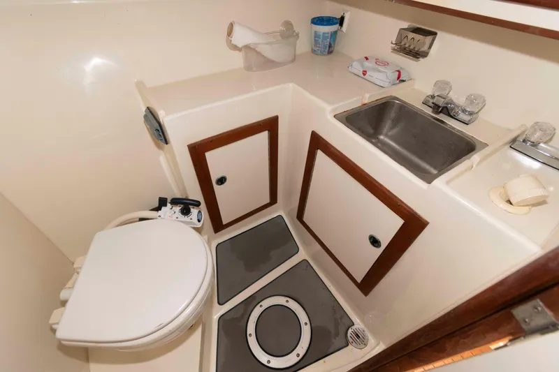 Slide: The Image of 1995 Albin 28 Tournament Express boat bathroom with toilet, sink, and storage cabinets. - 21