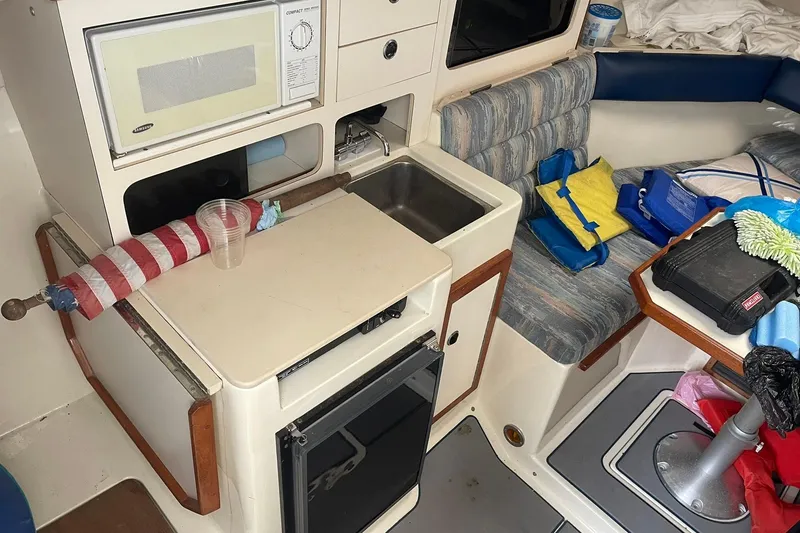 Slide: The Image of 1995 Albin 28 boat interior with seating and control panel, docked by the water. - 9