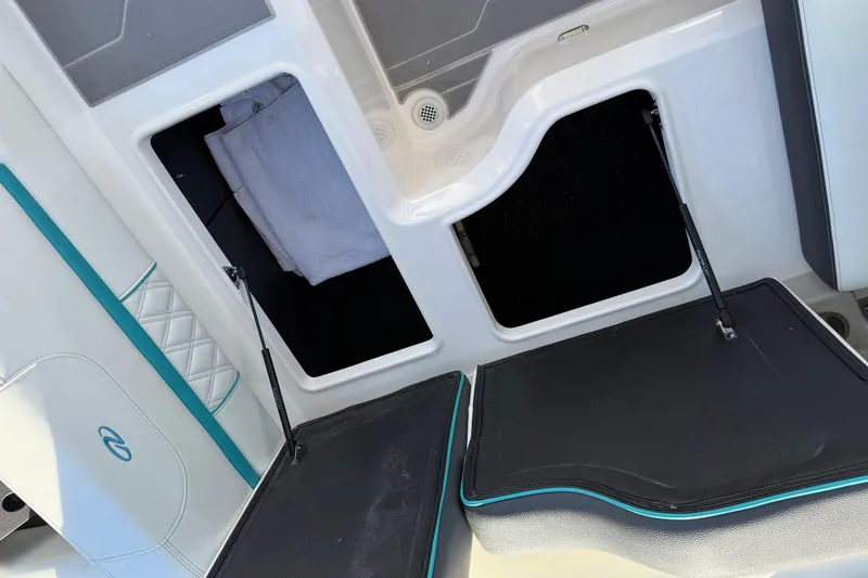 Slide: The Image of 2022 Regal LS2 boat interior storage compartments with open hatches and visible towel. - 11