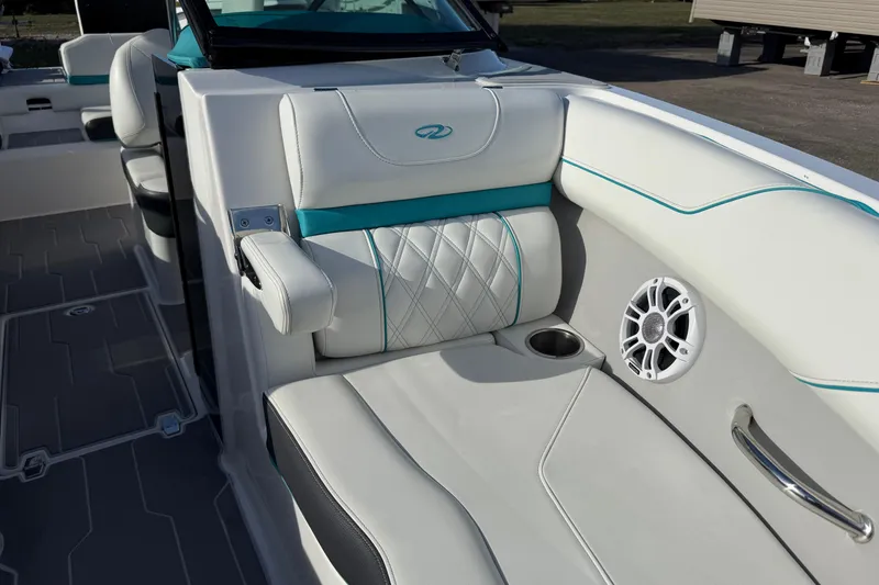 Slide: The Image of 2022 Regal LS2 boat interior with white and teal seating, speaker, and cup holder. - 12
