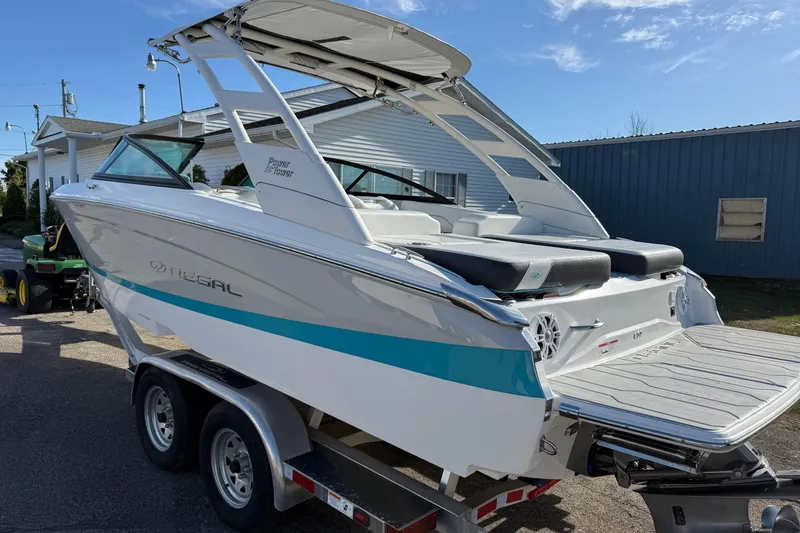 Slide: The Image of 2022 Regal LS2 boat on trailer, white and blue, parked outdoors. - 3
