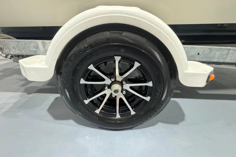Slide: The Image of 1989 Glastron/Carlson 19 CSS trailer wheel with black alloy rim and white fender. - 12
