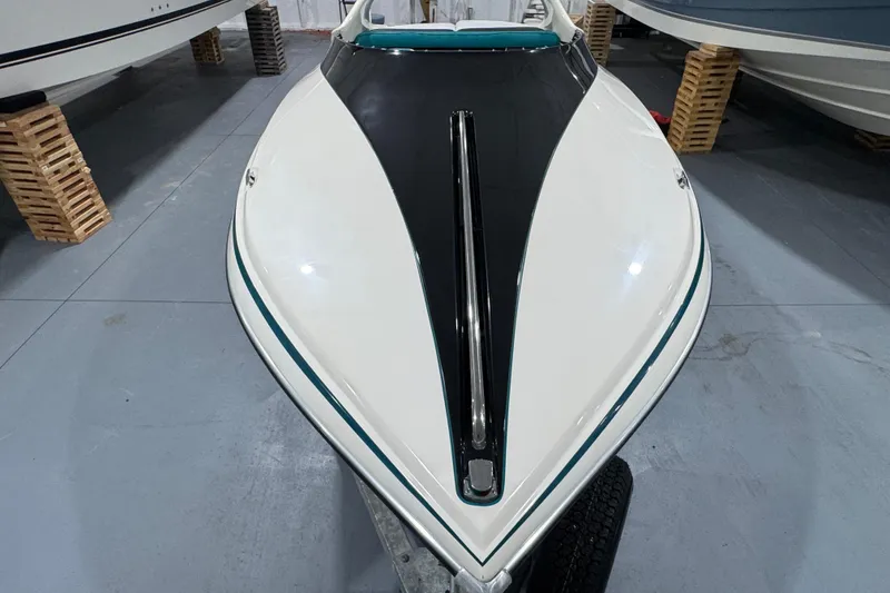 Slide: The Image of 1989 Glastron/Carlson 19 CSS boat, sleek white and black design, stored indoors. - 9