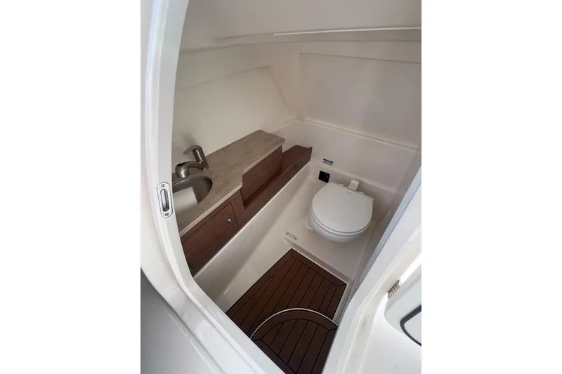 Slide: The Image of 2021 Boston Whaler 280 Vantage boat interior with compact bathroom and wooden accents. - 16