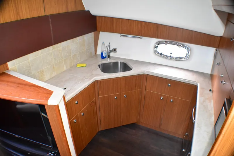 Slide: The Image of 2016 Tiara Yachts 4300 Open galley with wood cabinetry and stainless steel sink. - 26