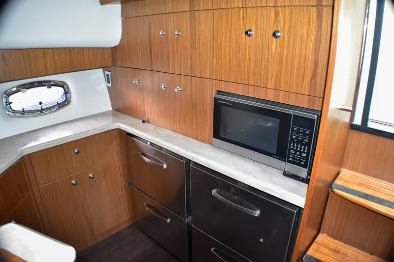 Slide: The Image of 2016 Tiara Yachts 4300 Open galley with wood cabinetry and modern appliances. - 27
