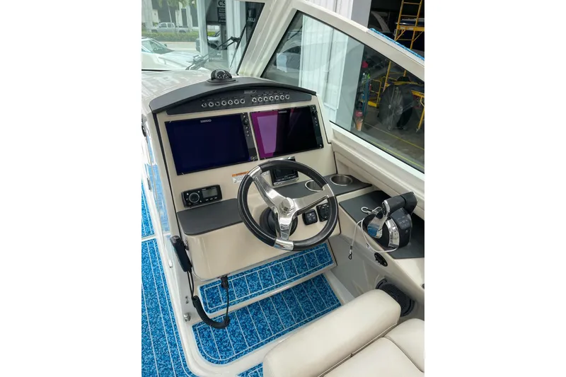 Slide: The Image of 2017 Boston Whaler 320 Vantage helm with dual screens and steering wheel. - 13