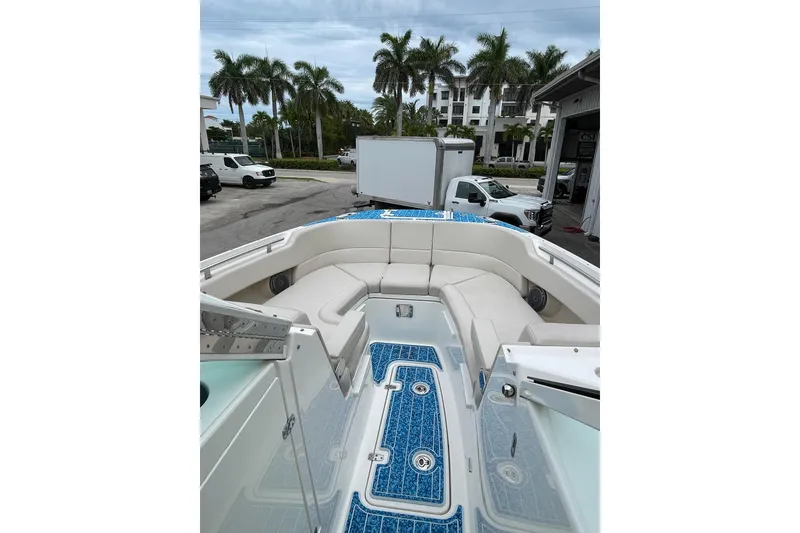 Slide: The Image of 2017 Boston Whaler 320 Vantage boat interior with seating and blue flooring, parked near palm trees. - 15