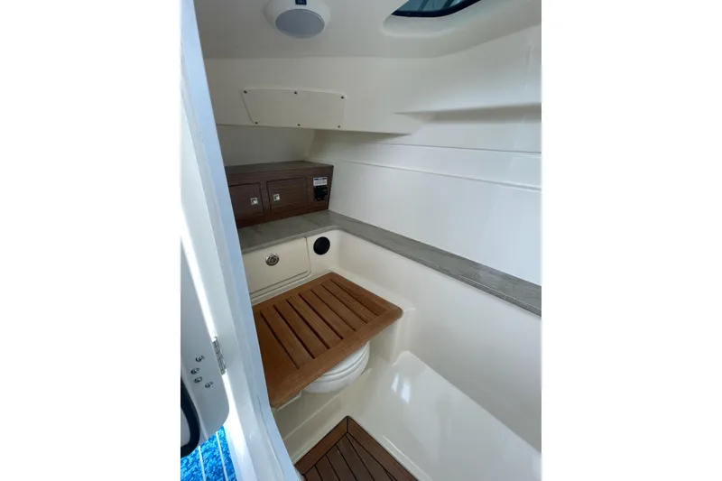 Slide: The Image of Interior of 2017 Boston Whaler 320 Vantage boat, featuring wooden accents and storage compartments. - 19