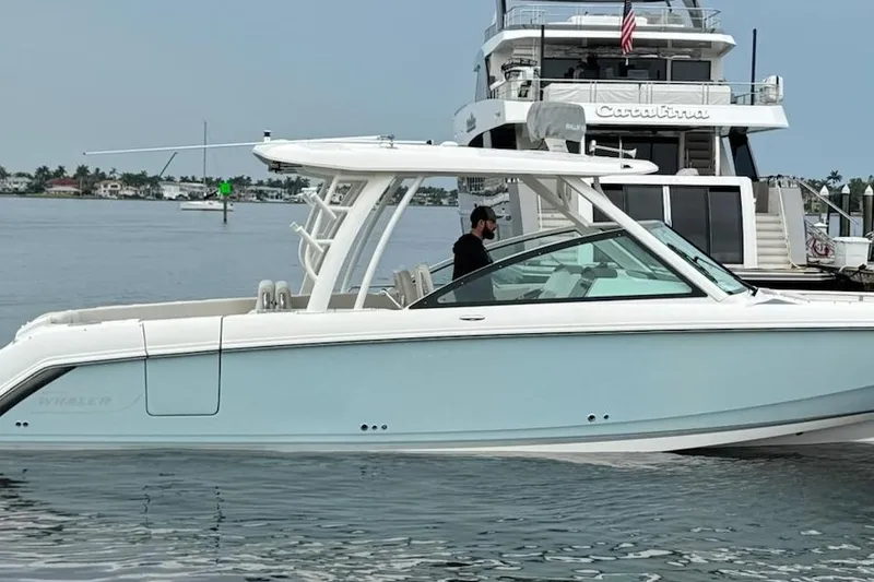 Slide: The Image of 2017 Boston Whaler 320 Vantage boat on calm water near a larger yacht. - 2