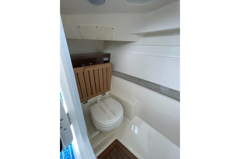 Slide: The Image of 2017 Boston Whaler 320 Vantage boat interior bathroom with toilet and wooden accents. - 20