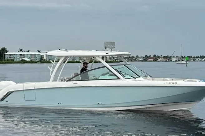 Slide: The Image of 2017 Boston Whaler 320 Vantage boat cruising on calm waters near coastal buildings. - 3
