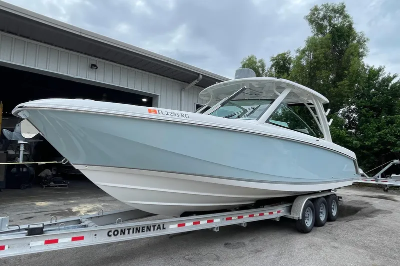 Slide: The Image of 2017 Boston Whaler 320 Vantage boat on trailer, parked outside a building. - 6
