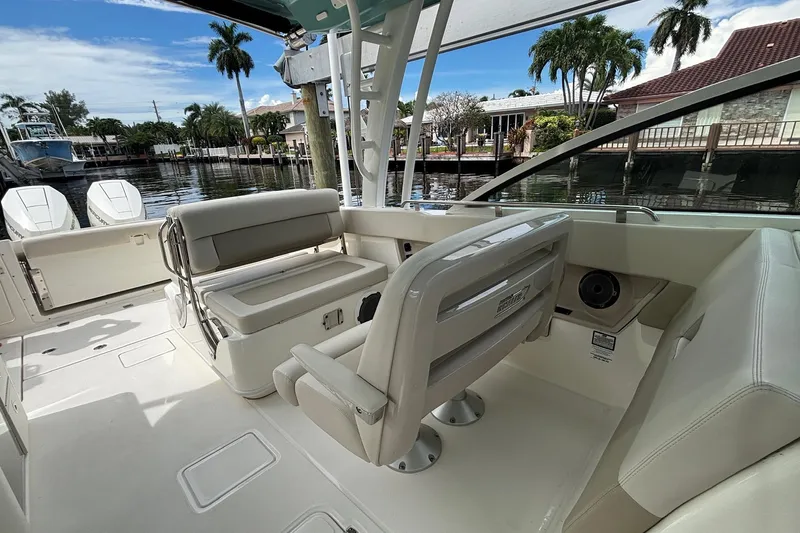 Slide: The Image of 2024 Boston Whaler 320 Vantage interior with seating, docked by waterfront homes. - 13