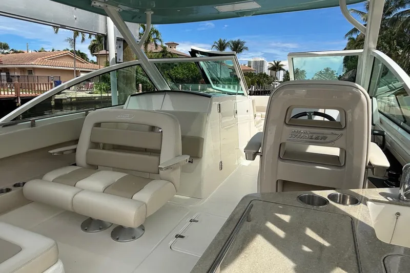 Slide: The Image of 2024 Boston Whaler 320 Vantage interior with seating and helm, dockside view. - 15