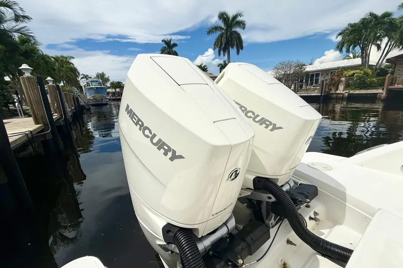 Slide: The Image of 2024 Boston Whaler 320 Vantage with twin Mercury outboard engines docked by palm trees. - 18