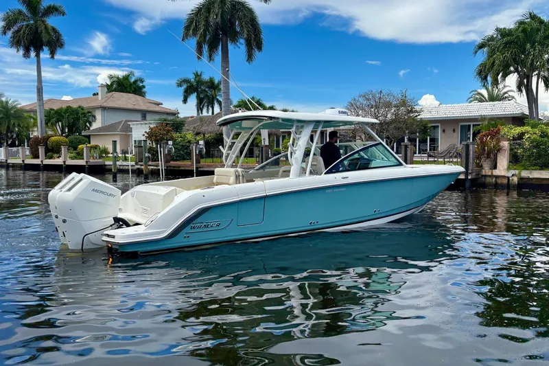 Slide: The Image of 2024 Boston Whaler 320 Vantage boat on a scenic waterway with palm trees. - 4