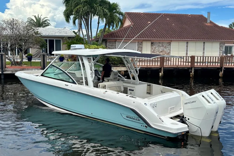 Slide: The Image of 2024 Boston Whaler 320 Vantage boat docked near waterfront home, featuring dual Mercury engines. - 5