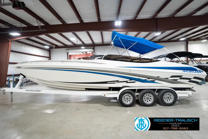 Slide: The Image of 2001 Nordic Heat 28 boat with blue canopy on trailer in indoor showroom. - 11