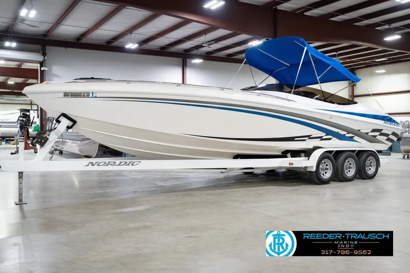 Slide: The Image of Nordic Heat 28 boat, 2001 model, in showroom with blue canopy and triple-axle trailer. - 4