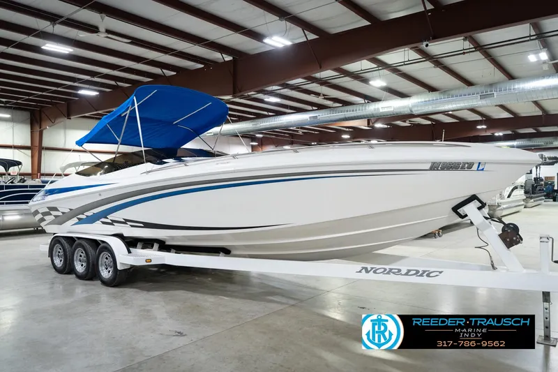 Slide: The Image of 2001 Nordic Heat 28 boat with blue canopy on trailer in indoor showroom. - 6