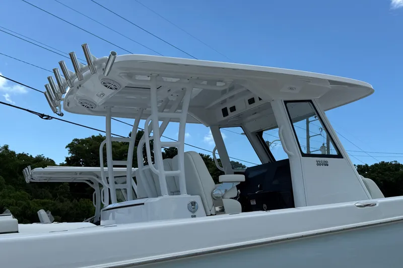 Slide: The Image of 2026 Everglades 335 Center Console boat with T-top and rod holders under clear sky. - 18