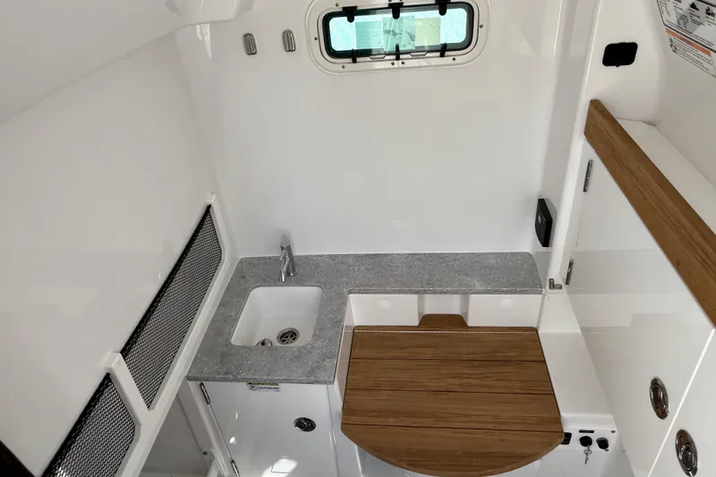 Slide: The Image of 2026 Everglades 335 Center Console interior with sink and wooden table. - 25