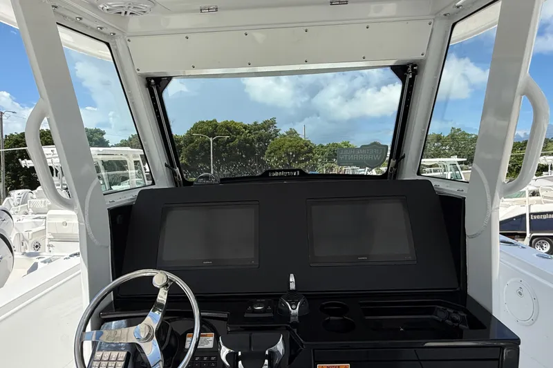 Slide: The Image of 2026 Everglades 335 Center Console boat dashboard with dual screens and steering wheel. - 33