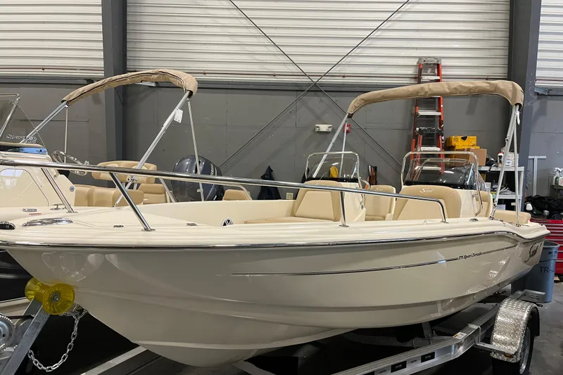 The Image of 2025 Scout 175 Sport Dorado boat in showroom, featuring sleek design and beige seating. - 0