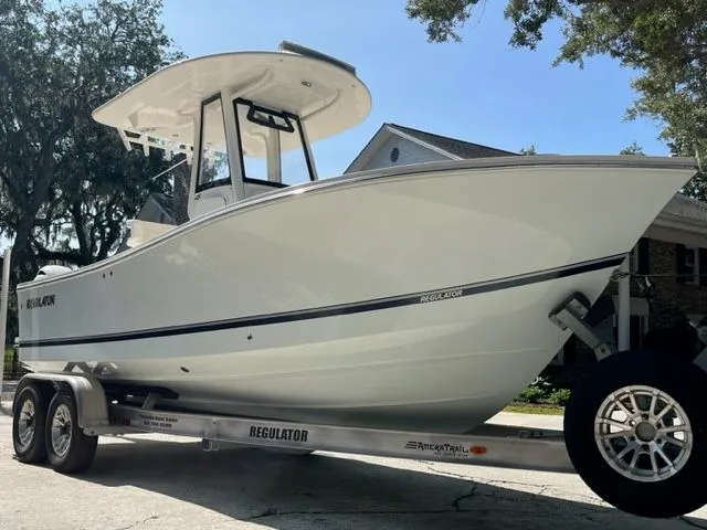 The Image of 2022 Regulator 23 CC boat on trailer, parked outdoors under clear sky. - 0