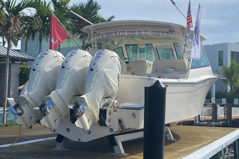 Slide: The Image of 2024 Grady-White Freedom 375 boat with triple outboard engines docked by palm trees. - 25