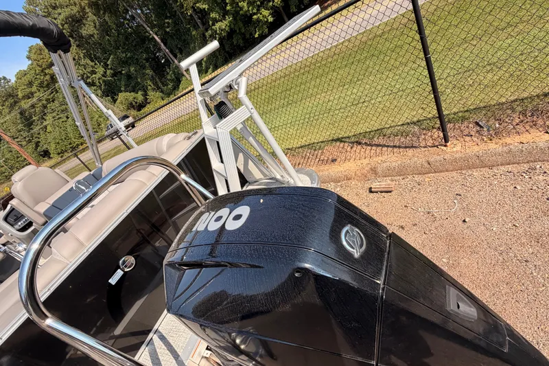 Slide: The Image of 2022 Avalon 2585 ENT Catalina Platinum boat with powerful outboard motor, parked near a fence. - 7