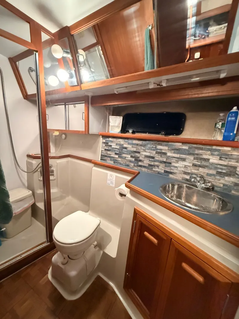 Slide: The Image of 1987 Carver 42 Cockpit Motor Yacht bathroom with shower, sink, and wood cabinetry. - 17