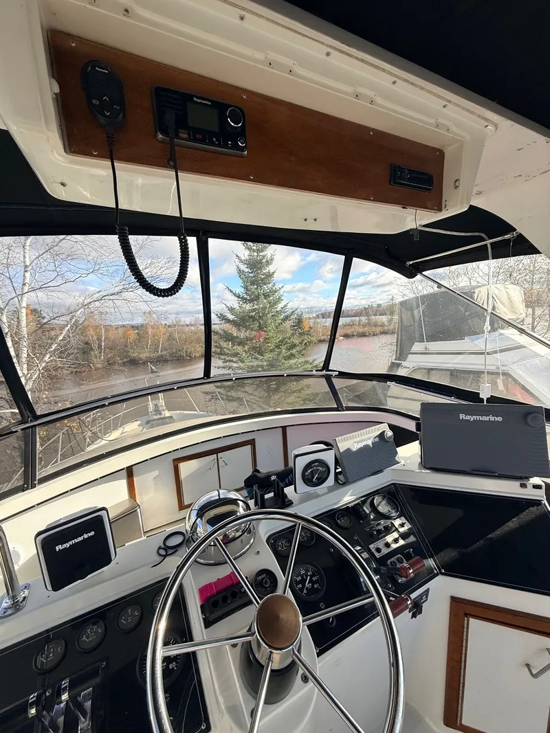 Slide: The Image of 1987 Carver 42 Cockpit Motor Yacht helm with Raymarine electronics and scenic river view. - 19