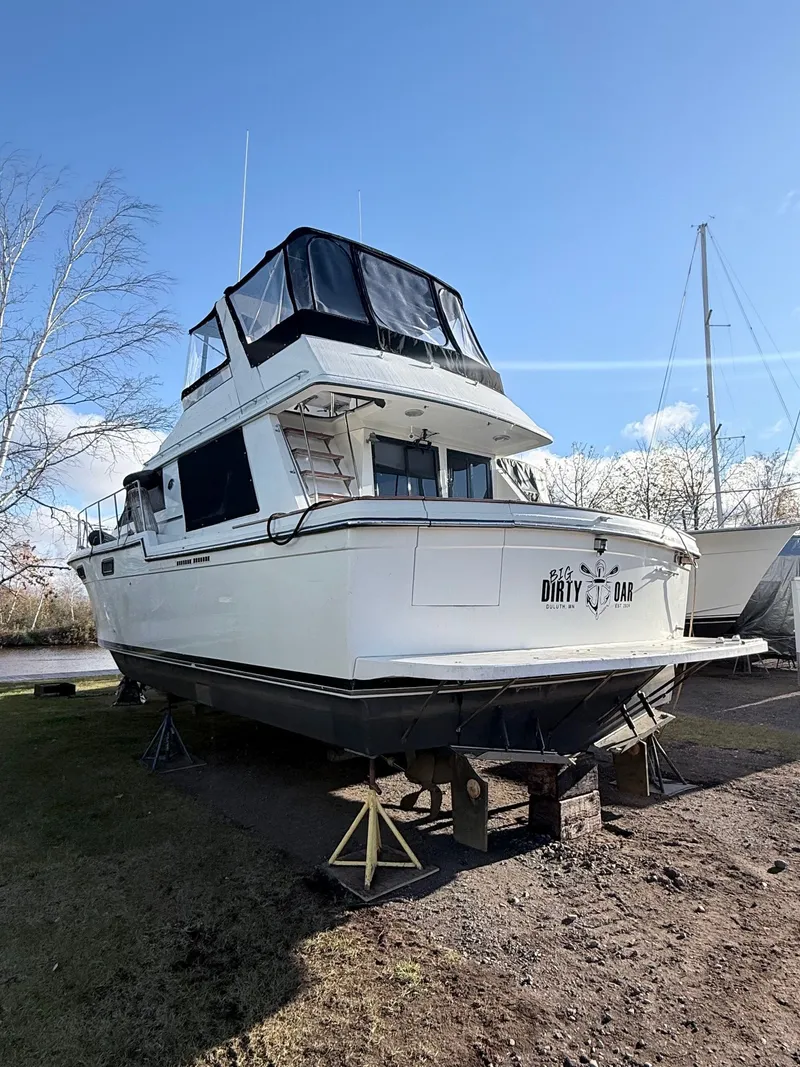 Slide: The Image of 1987 Carver 42 Cockpit Motor Yacht on land, named "Dirty Oar," under clear blue sky. - 4