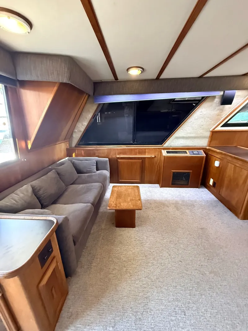 Slide: The Image of 1987 Carver 42 Cockpit Motor Yacht interior with sofa, wooden table, and large windows. - 10