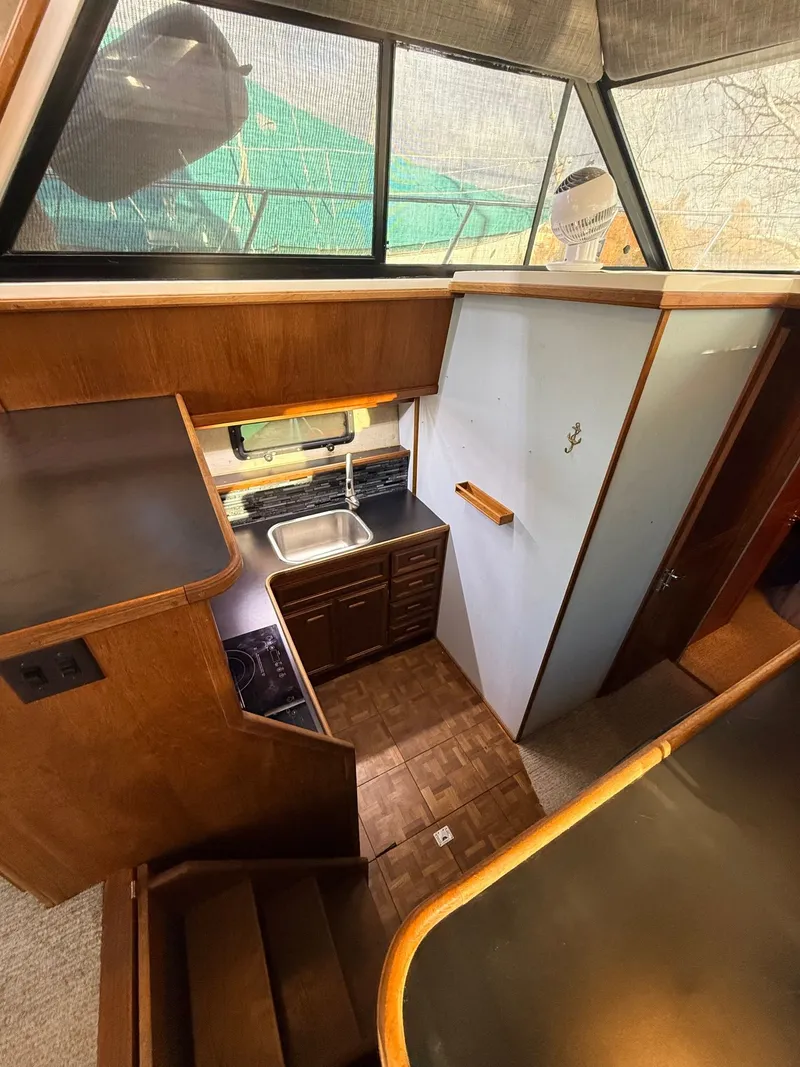 Slide: The Image of 1987 Carver 42 Cockpit Motor Yacht interior with kitchen, wood cabinetry, and stairs. - 11