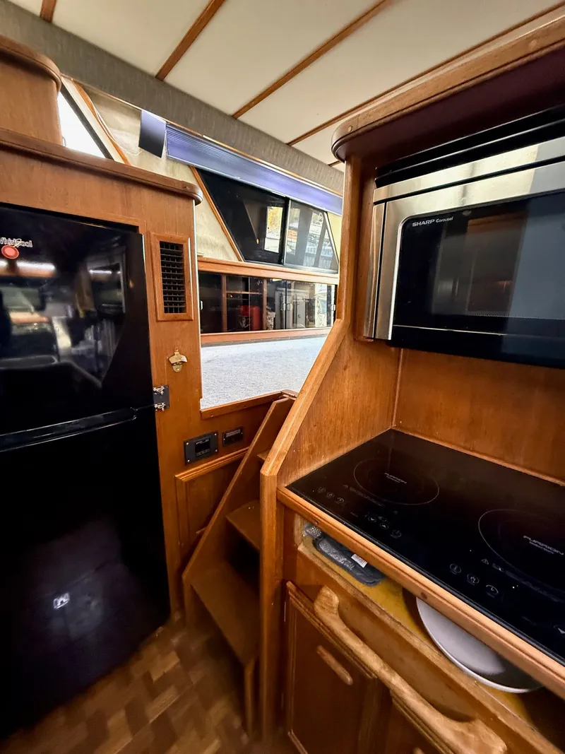 Slide: The Image of 1987 Carver 42 Cockpit Motor Yacht kitchen with stove, microwave, and refrigerator. - 13