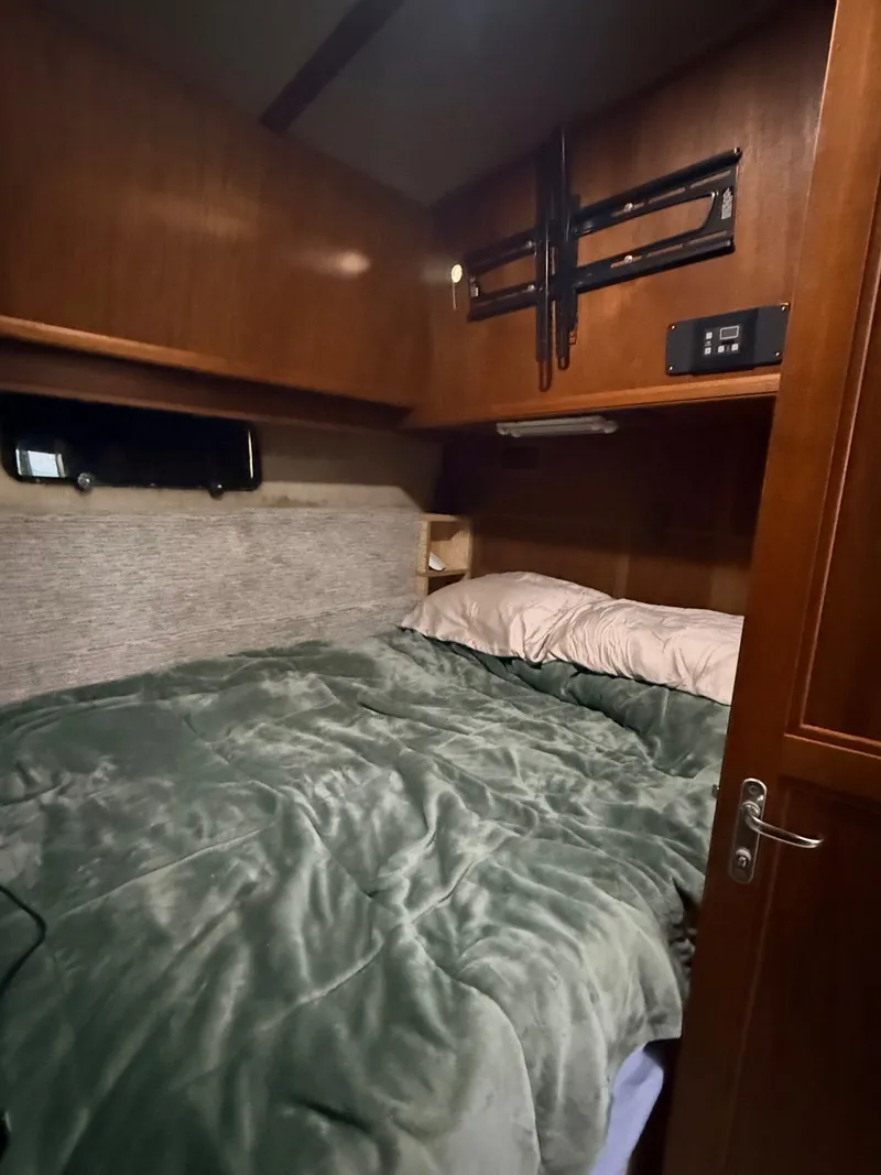 Slide: The Image of Cozy bedroom in 1987 Carver 42 Cockpit Motor Yacht with green bedding and wood paneling. - 14