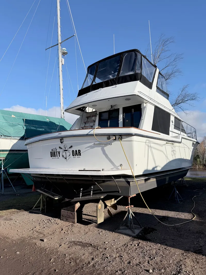 Slide: The Image of 1987 Carver 42 Cockpit Motor Yacht on dry dock, labeled "Dirty Oar," under clear blue sky. - 3