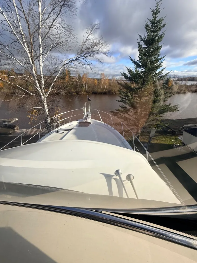 Slide: The Image of 1987 Carver 42 Cockpit Motor Yacht docked by a scenic river with autumn trees. - 6