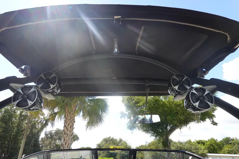 Slide: The Image of 2019 Malibu Wakesetter 23 LSV boat speakers under canopy, sunny day, palm trees. - 10