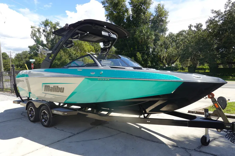 Slide: The Image of 2019 Malibu Wakesetter 23 LSV boat on trailer, teal and black design, parked outdoors. - 3