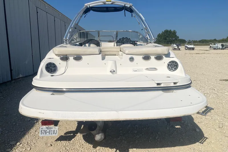 Slide: The Image of 2012 Bayliner 235 Bowrider boat, rear view, parked on gravel near storage facility. - 3