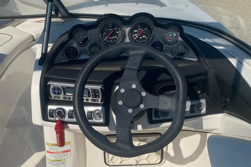 Slide: The Image of Steering wheel and dashboard of 2012 Bayliner 235 Bowrider boat, featuring gauges and controls. - 6