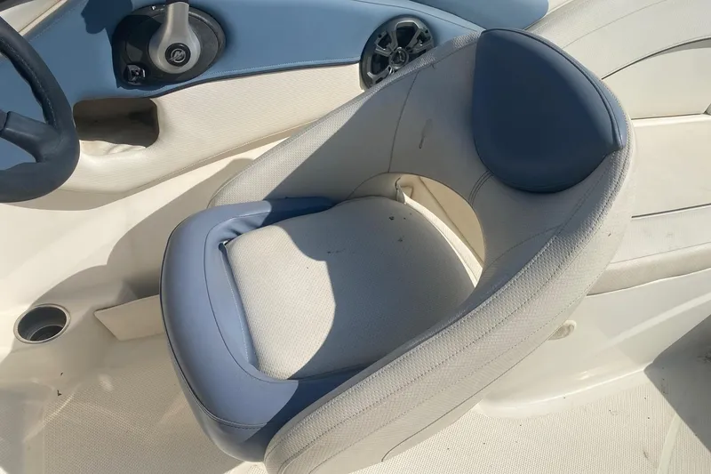 Slide: The Image of 2012 Bayliner 235 Bowrider cockpit with blue and white seating, steering wheel, and cup holder. - 7