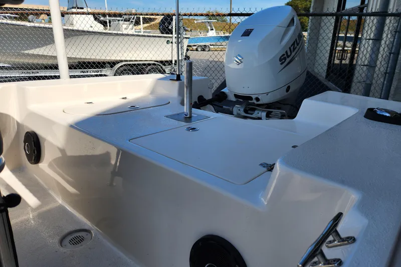 Slide: The Image of 2025 Carolina Skiff 178 JLS boat with Suzuki outboard motor, docked near a fence. - 11