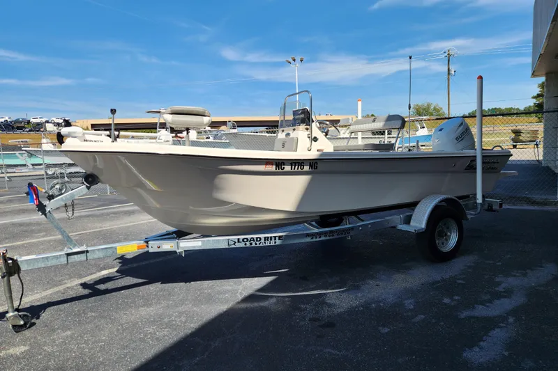 Slide: The Image of 2025 Carolina Skiff 178 JLS boat on trailer, parked outdoors under clear blue sky. - 5
